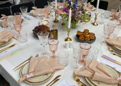 Nærbillede af fuldt opdækket borde med pink servietter og mad til bryllupsmiddage på Skabelonloftet